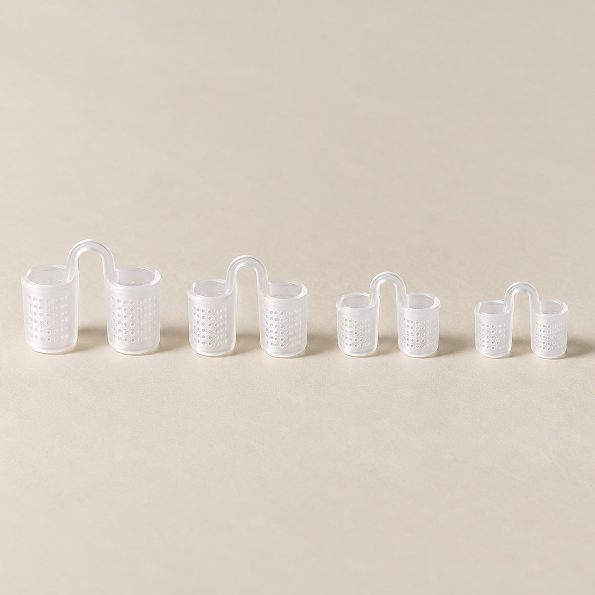 Os quatro tamanhos do dilatador nasal de silicone transparente, com telinha, do maior ao menor, sobre fundo claro.