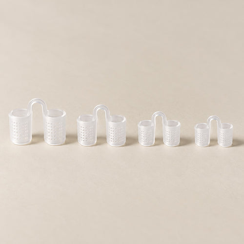 Os quatro tamanhos do dilatador nasal de silicone transparente, com telinha, do maior ao menor, sobre fundo claro.