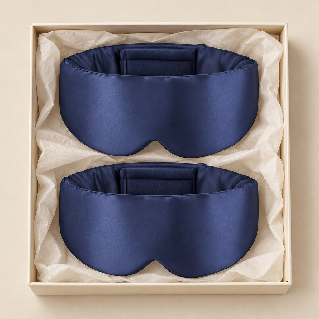 Par de máscaras de dormir de seda azul-marinho envolventes em caixa neutra, vista de cima