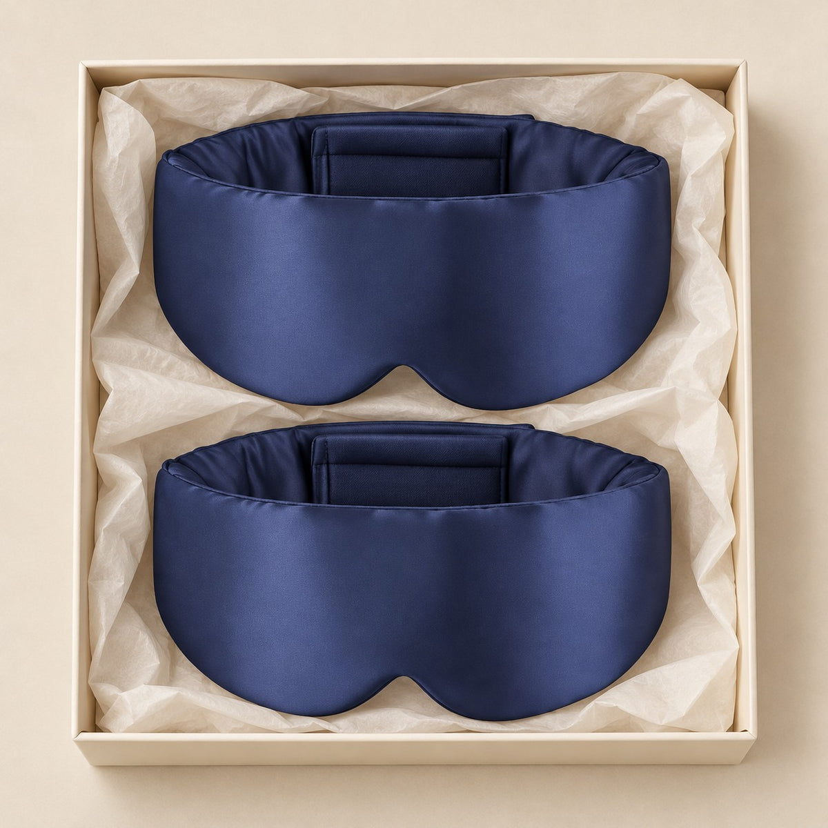 Par de máscaras de dormir de seda azul-marinho envolventes em caixa neutra, vista de cima